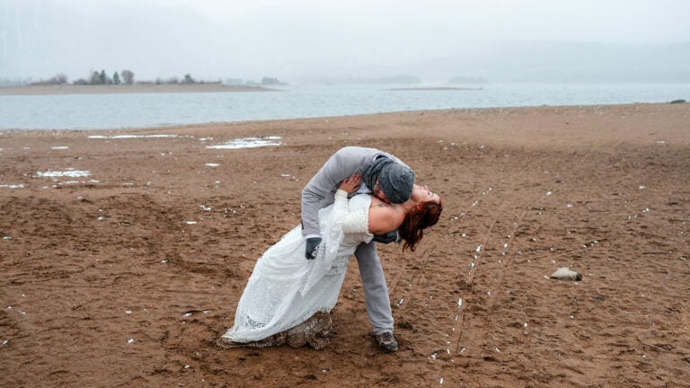 Couple embracing on sandy lakeshore.