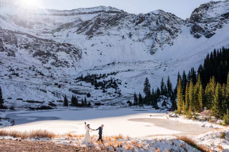 Couple celebrating winter elopement by frozen Colorado lake