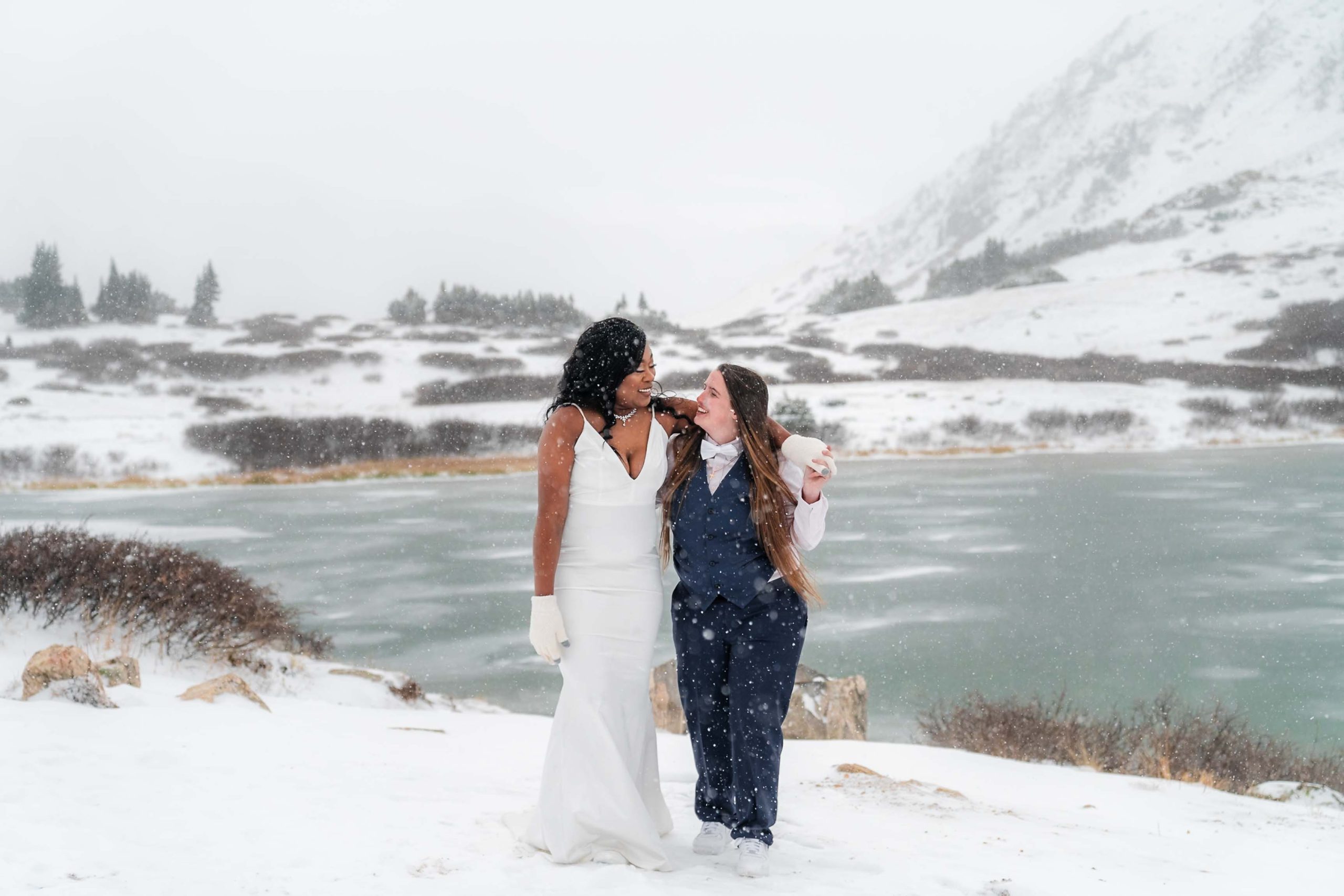 two brides smiling together in a snowy winter landscape