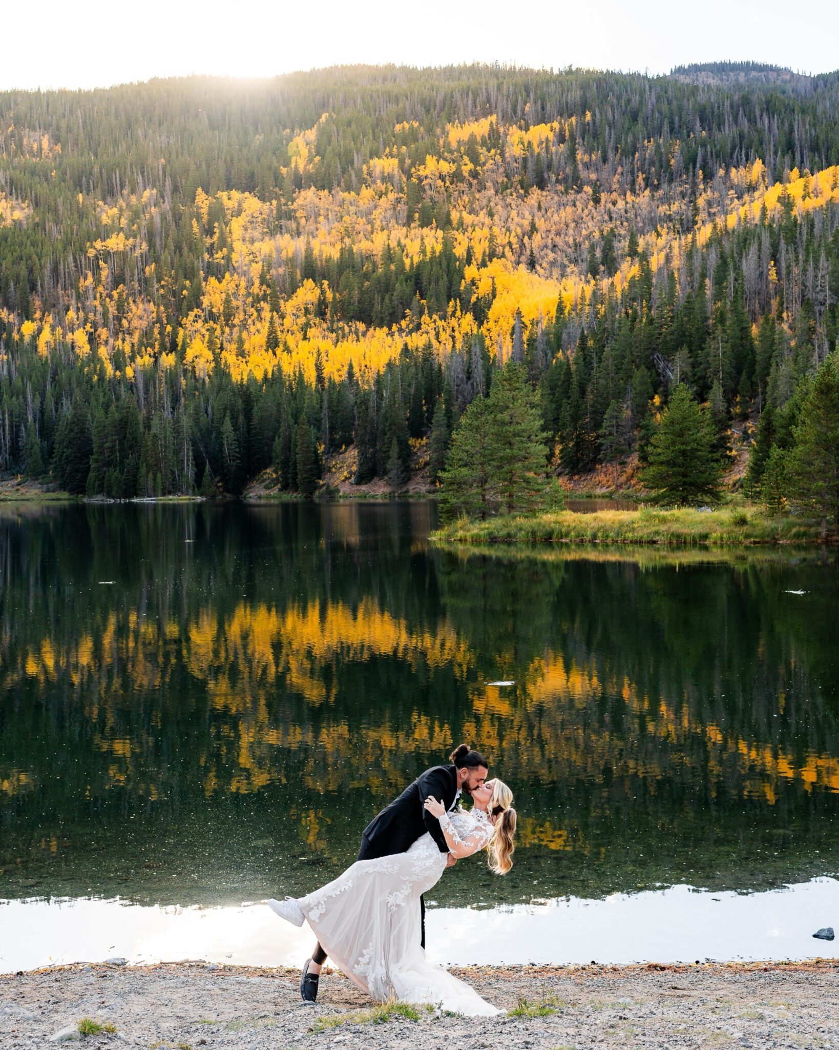 Fall Colorado elopement with golden aspen trees—bride and groom sharing a kiss beside alpine lake. 