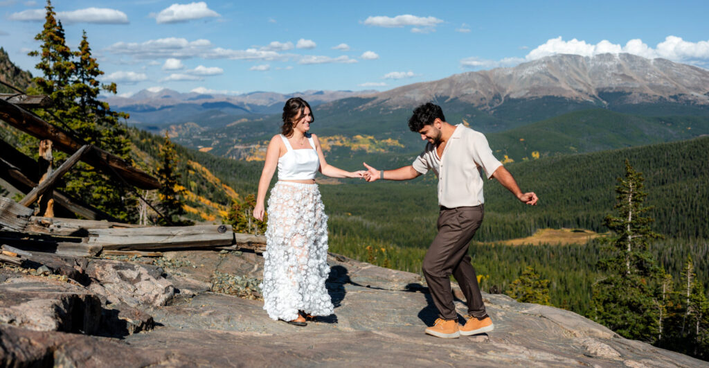 Couple dancing in scenic mountain landscape.